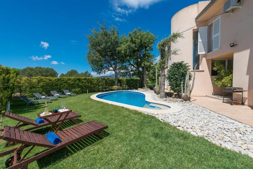 Un patio ajardinado con piscina, césped y asientos al aire libre.