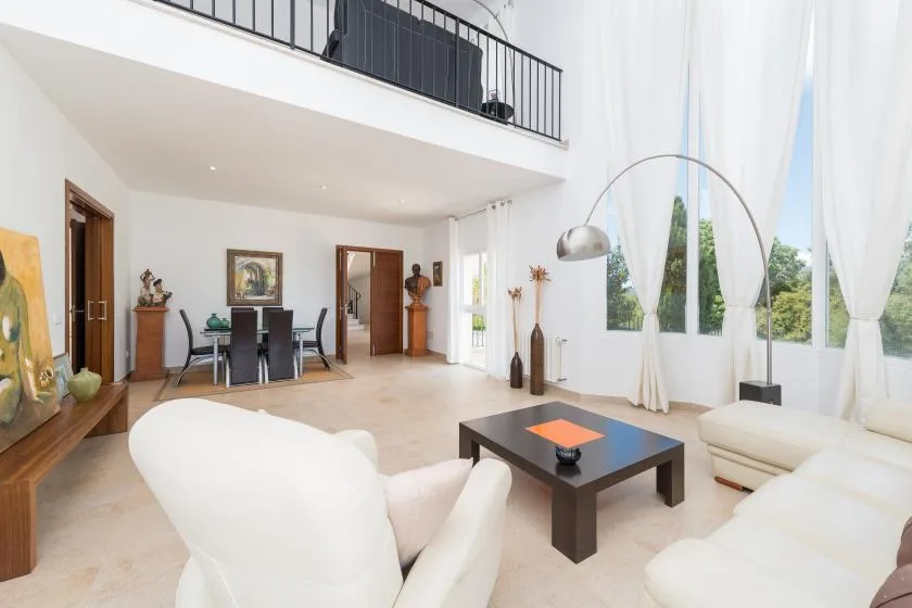 Una sala luminosa con asientos, una mesa de centro y ventanas altas.
