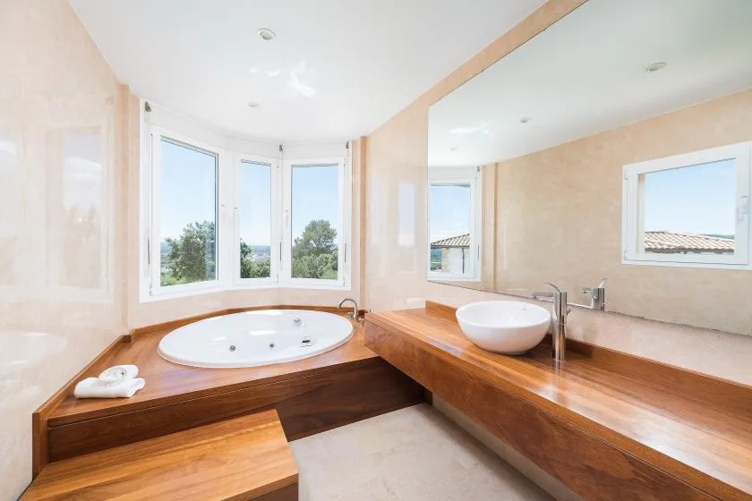 Un baño con una bañera empotrada bajo ventanas amplias.