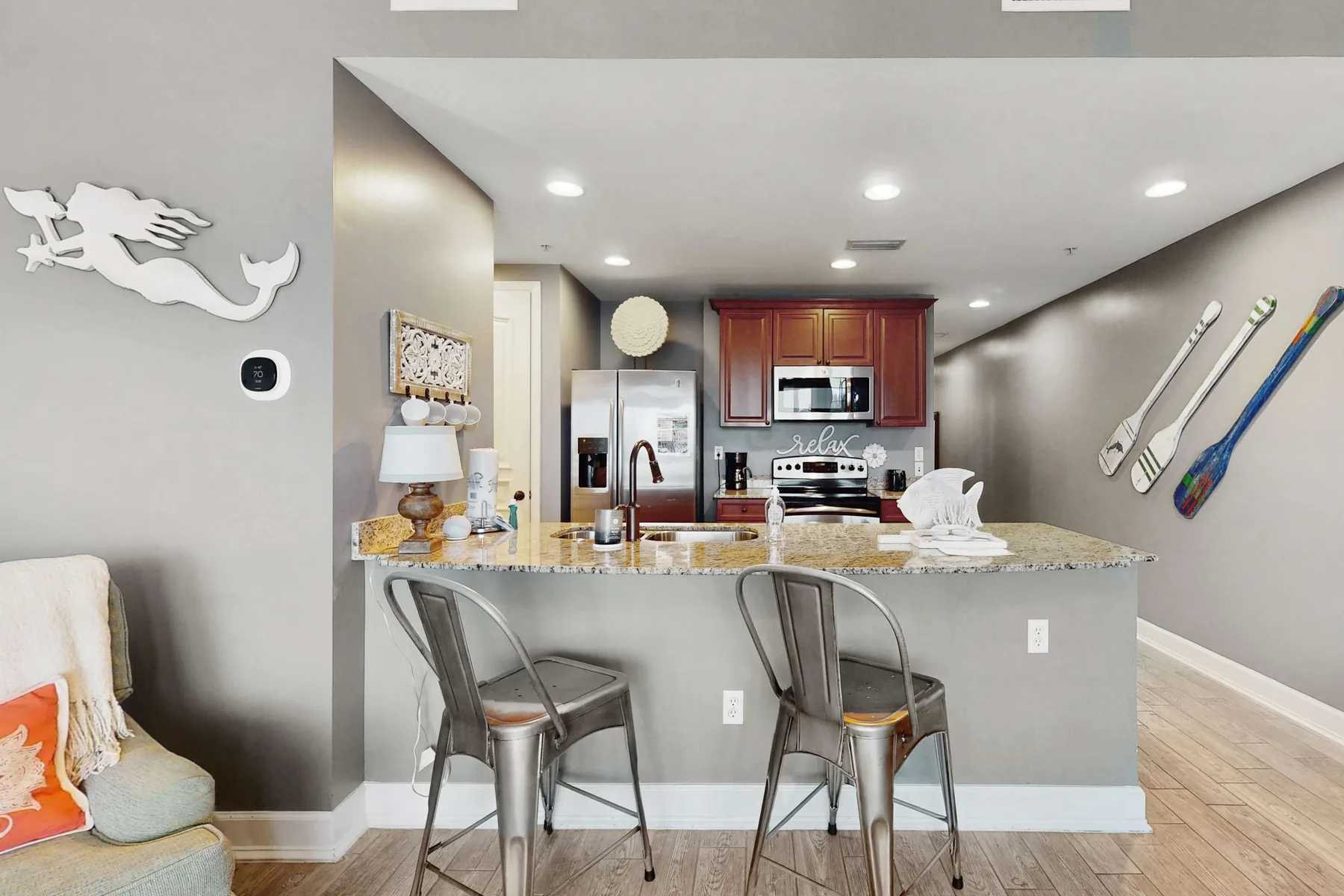 A kitchen with a stone island, metal seating, and stainless steel appliances.