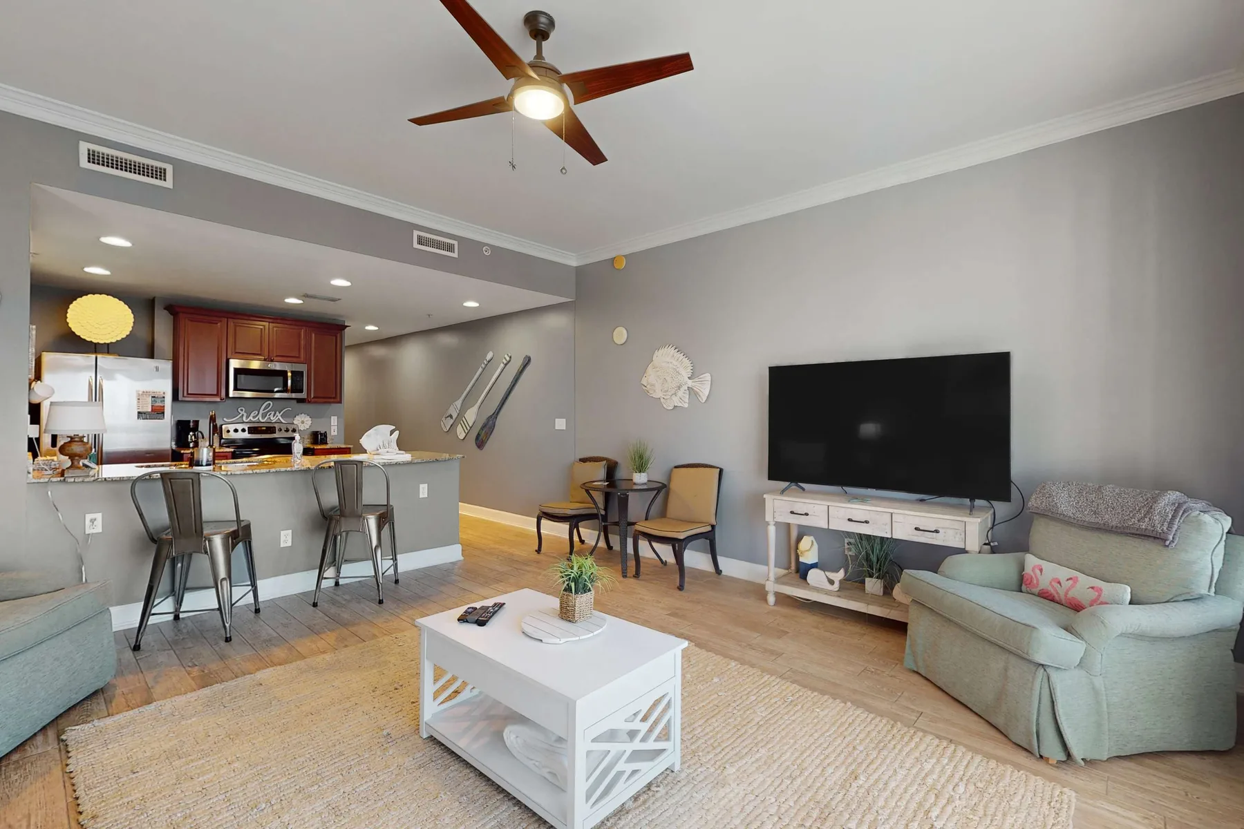 A living room opens onto a kitchen, with seating around a coffee table and television.