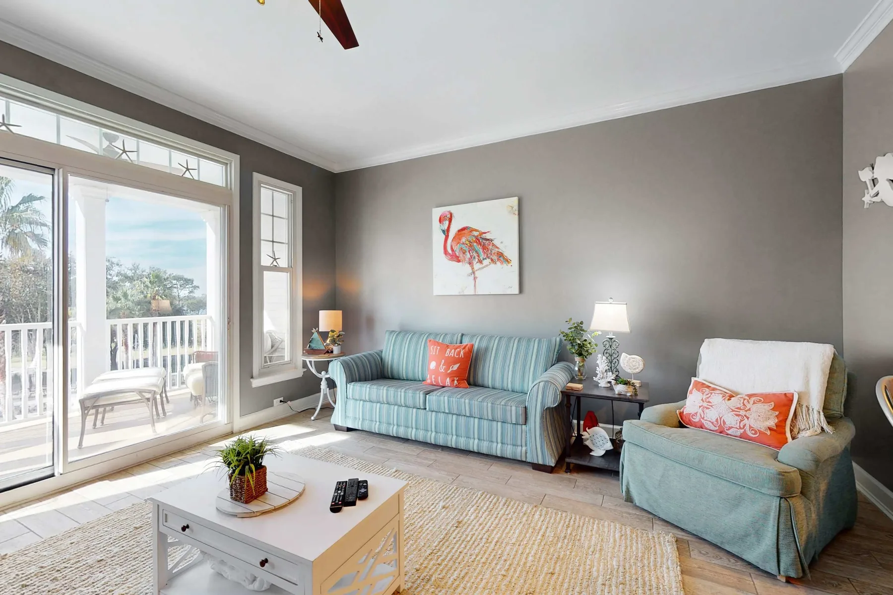 A bright living room with blue seating, a coffee table, and sliding glass doors.