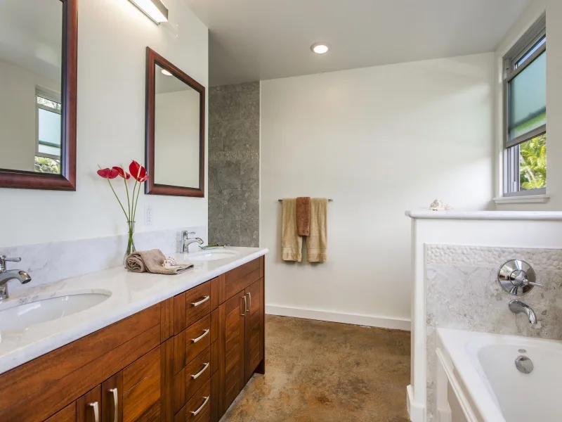 Un baño luminoso con un tocador largo y una bañera junto a una ventana.