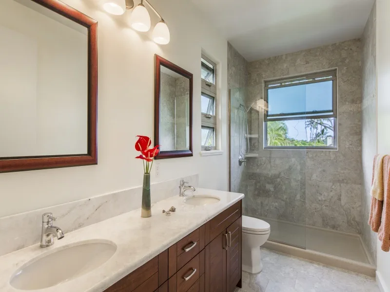 Un baño con un lavabo largo, espejos y una bañera debajo de una ventana.