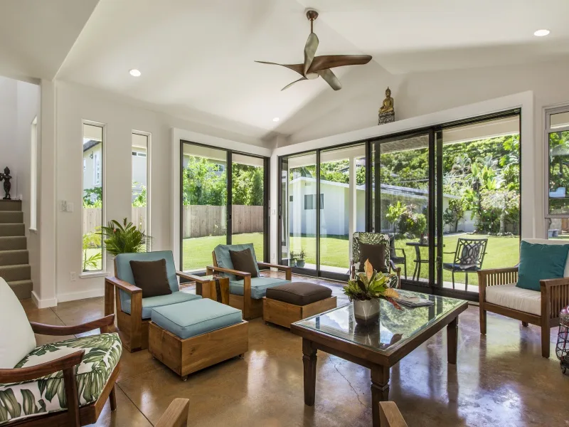 Una sala luminosa con asientos, una mesa de centro y amplias ventanas con vistas al jardín.