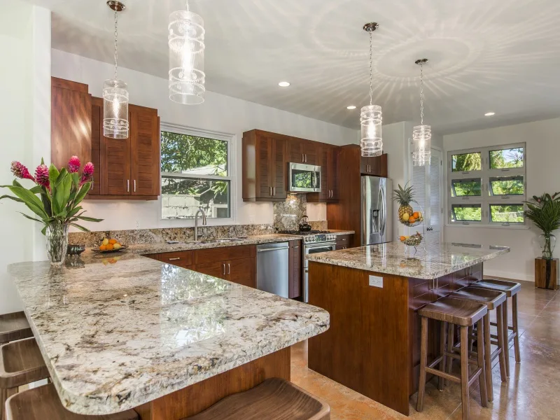 Una cocina luminosa con gabinetes de madera, encimeras de piedra y una isla central.