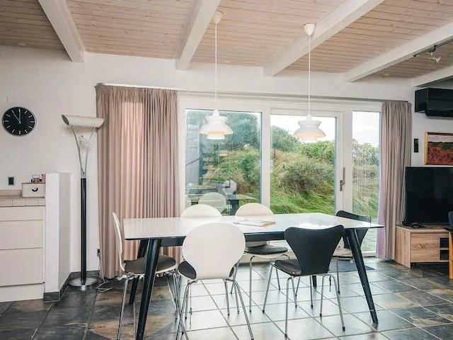 A dining area with a table and chairs beside large windows.
