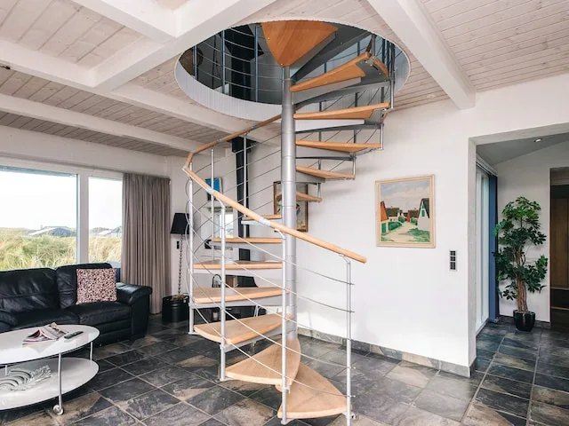 A bright living room features a spiral staircase beside dark seating.