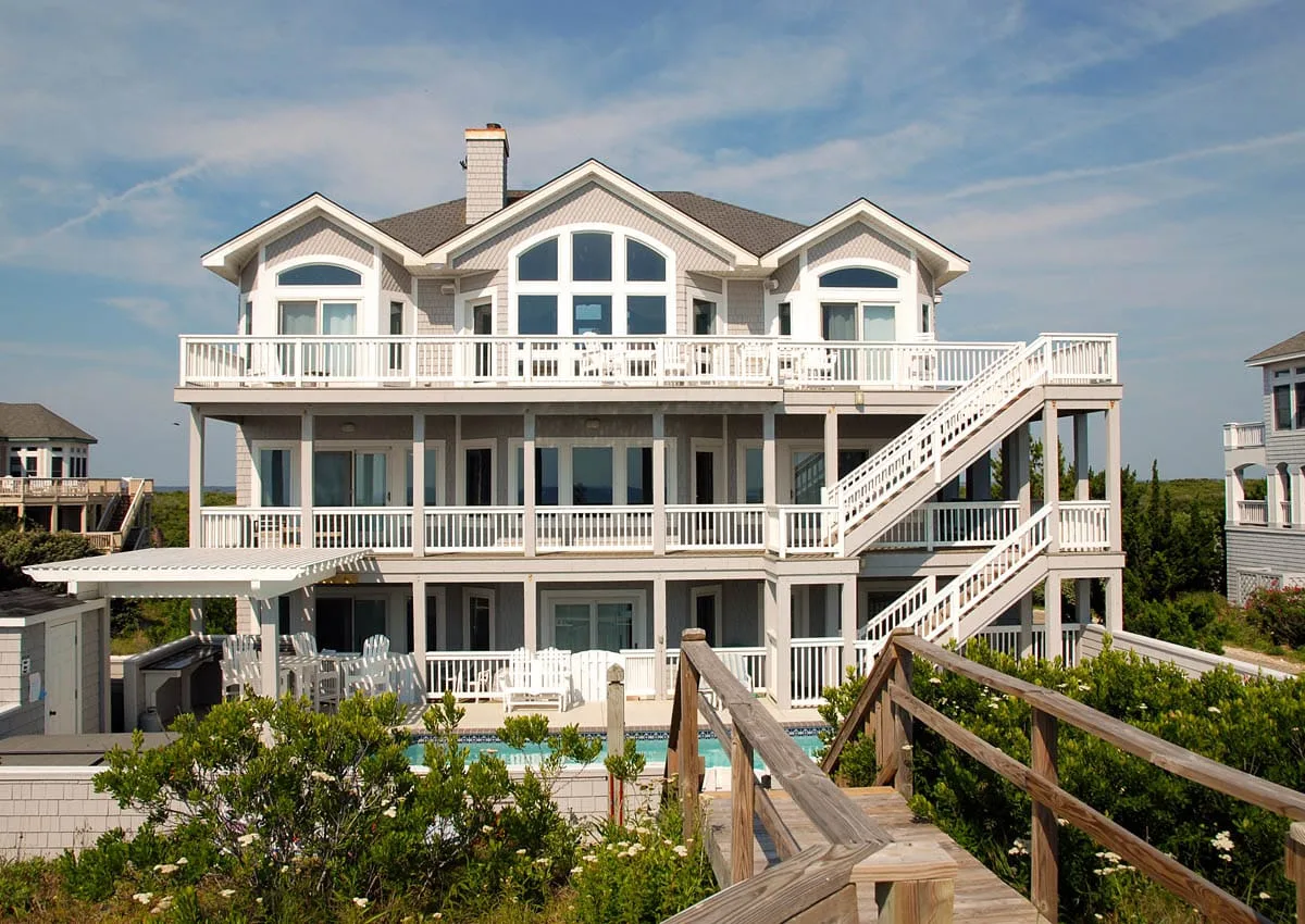 A large coastal-style house with white balconies and an exterior staircase.