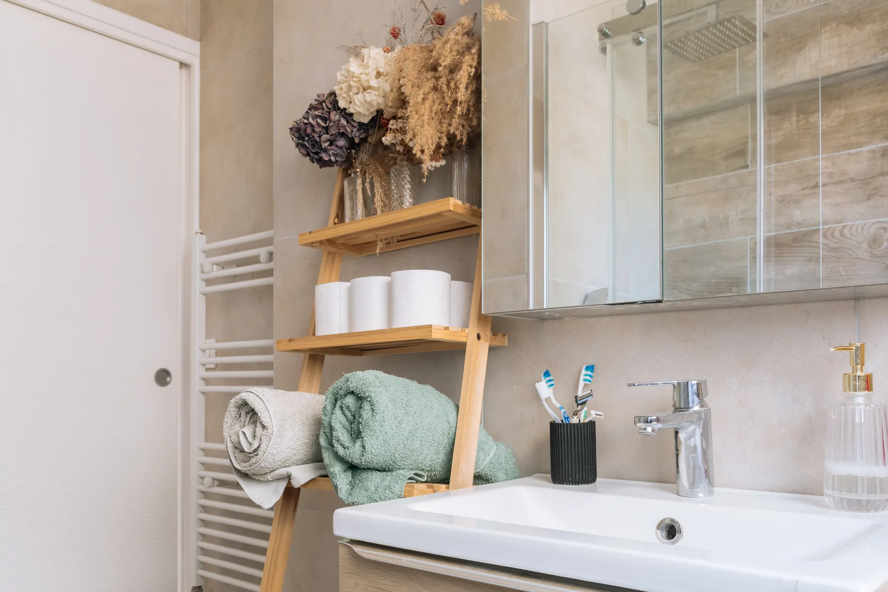 Un lavabo de baño con espejo y toallas sobre una repisa de madera.