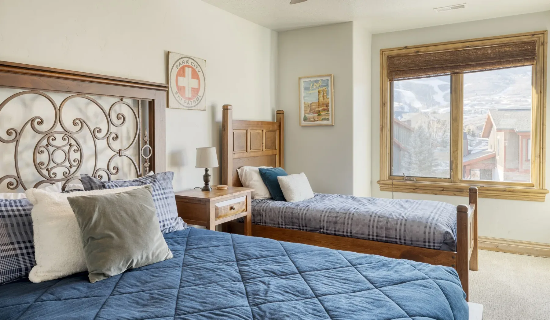 A bedroom with two beds, bedside tables, and a large window.