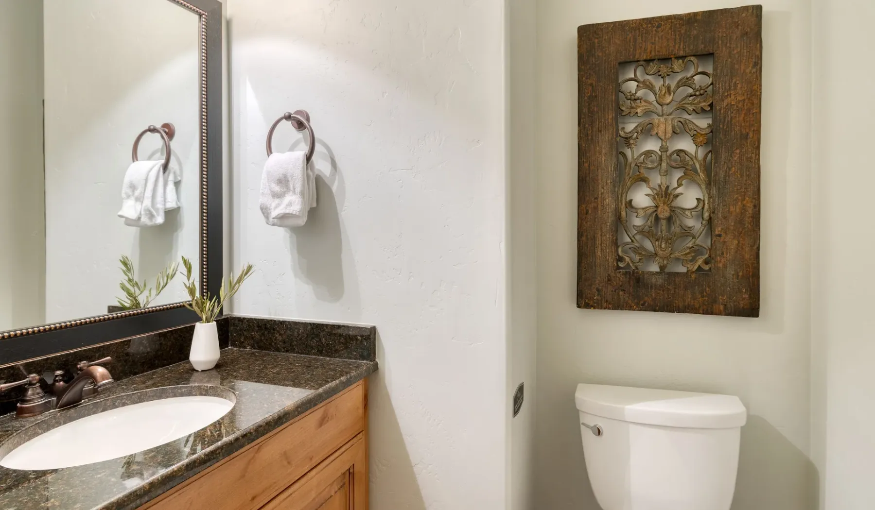 A bathroom vanity and toilet are shown beneath a wall-mounted decorative panel.
