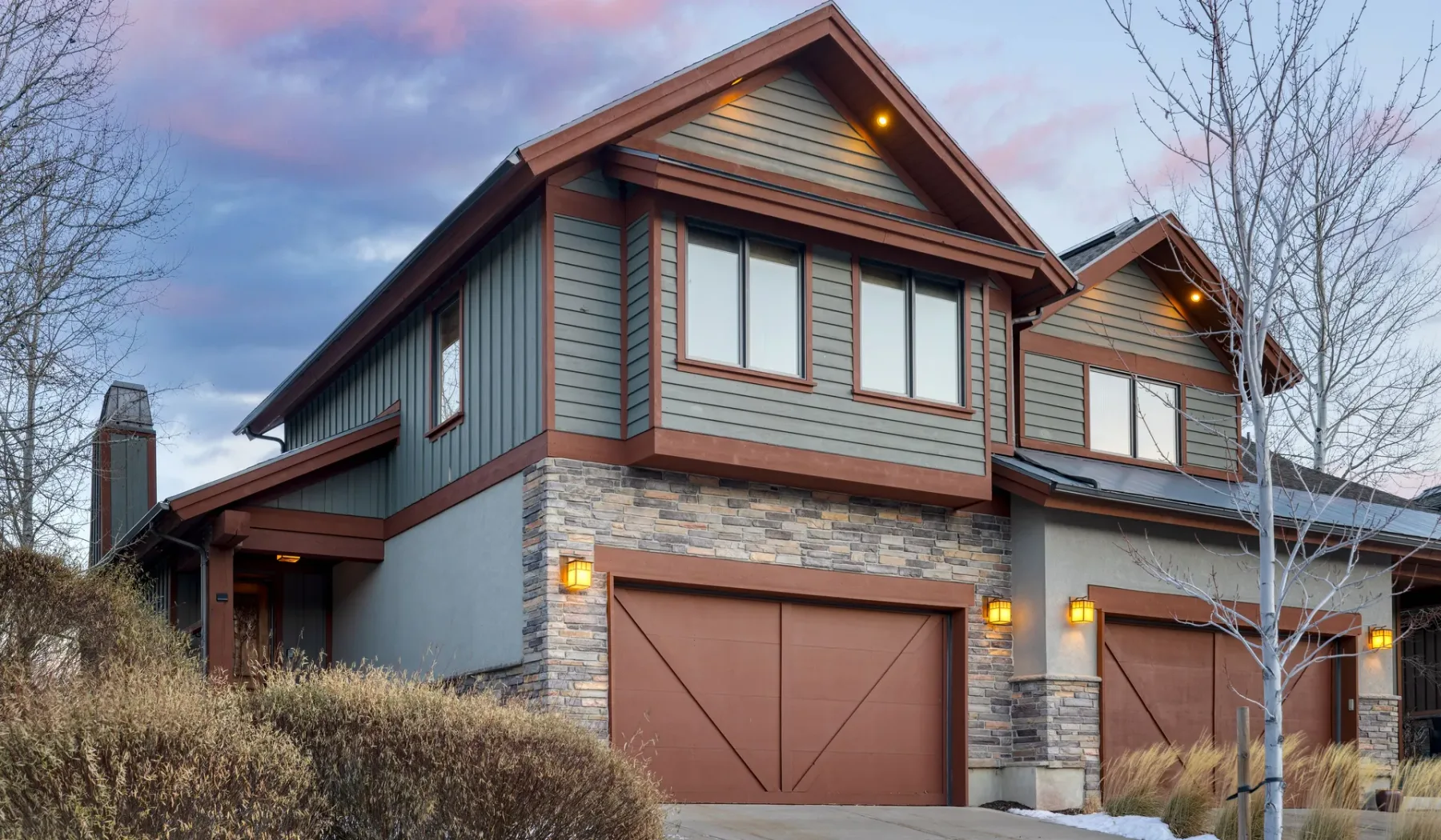 Exterior view of a multi-level house with stone accents and garage doors.
