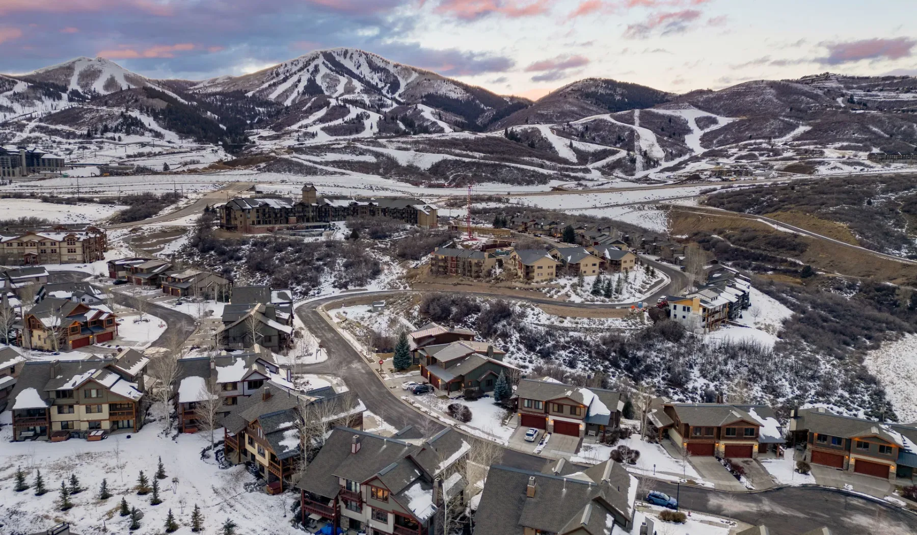 A snowy mountain village with winding roads below ski trails.