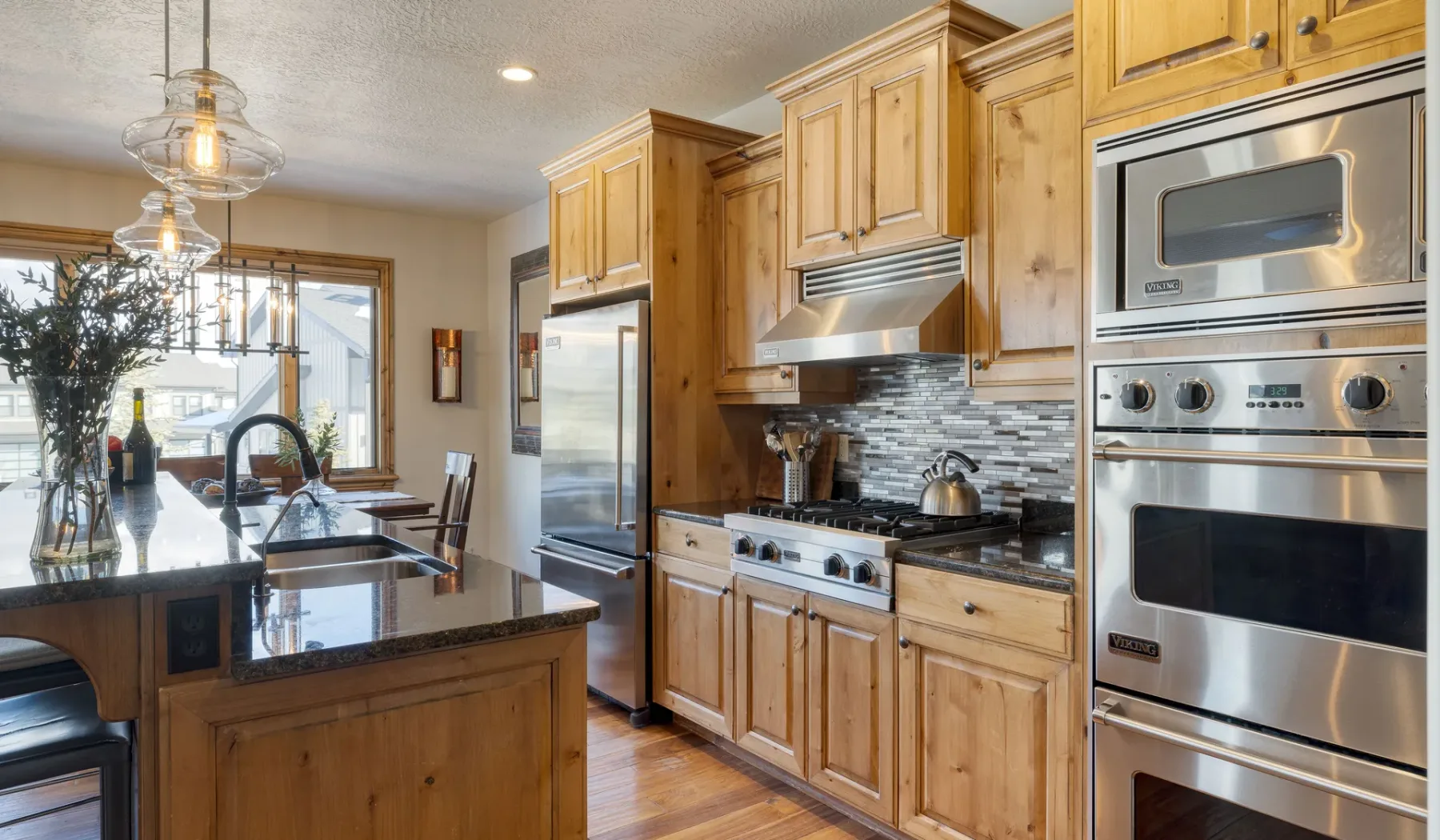 A bright kitchen with wooden cabinets, stainless steel appliances, and a central island.