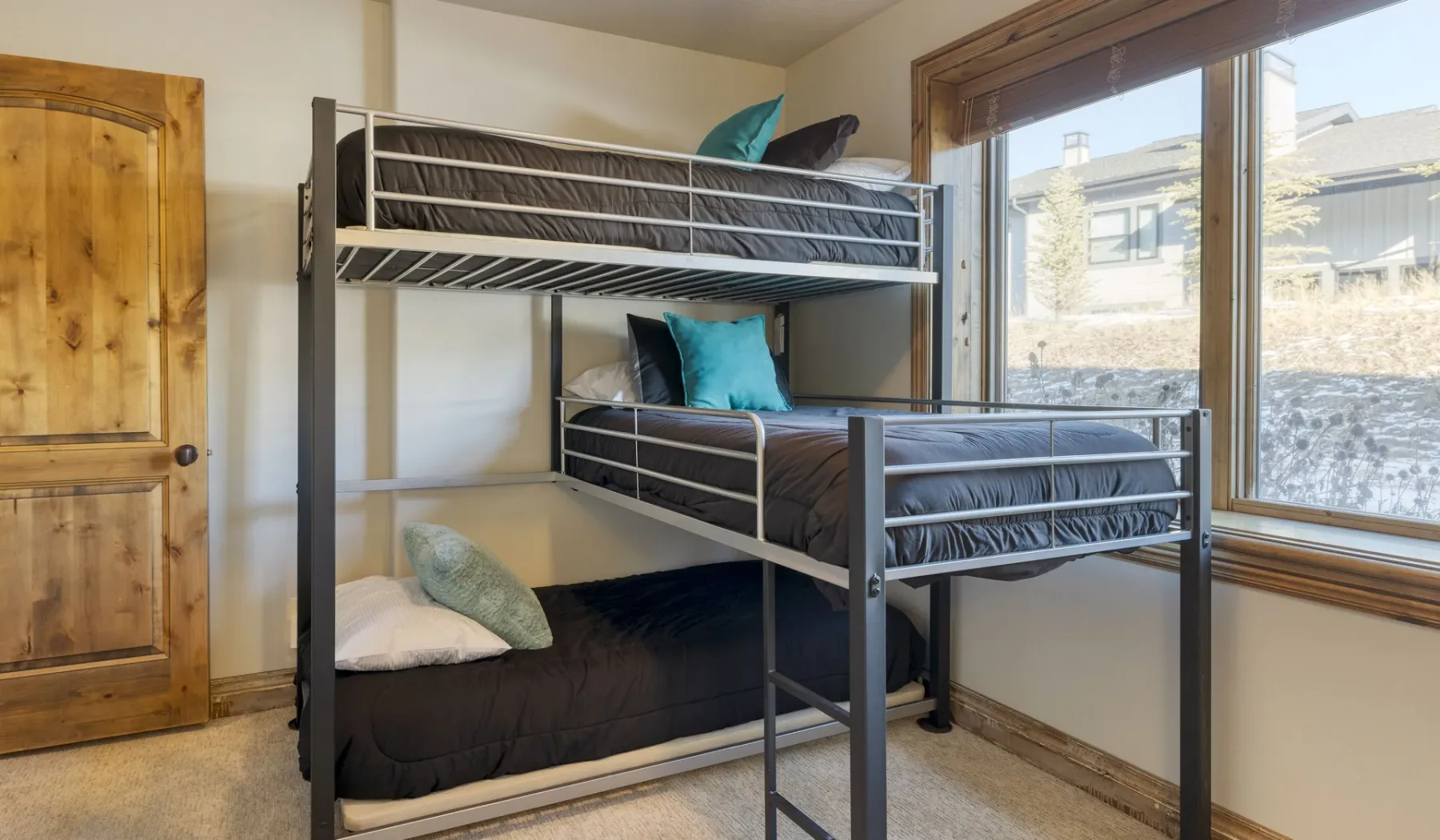 A bedroom with a metal bunk bed beside a large window.