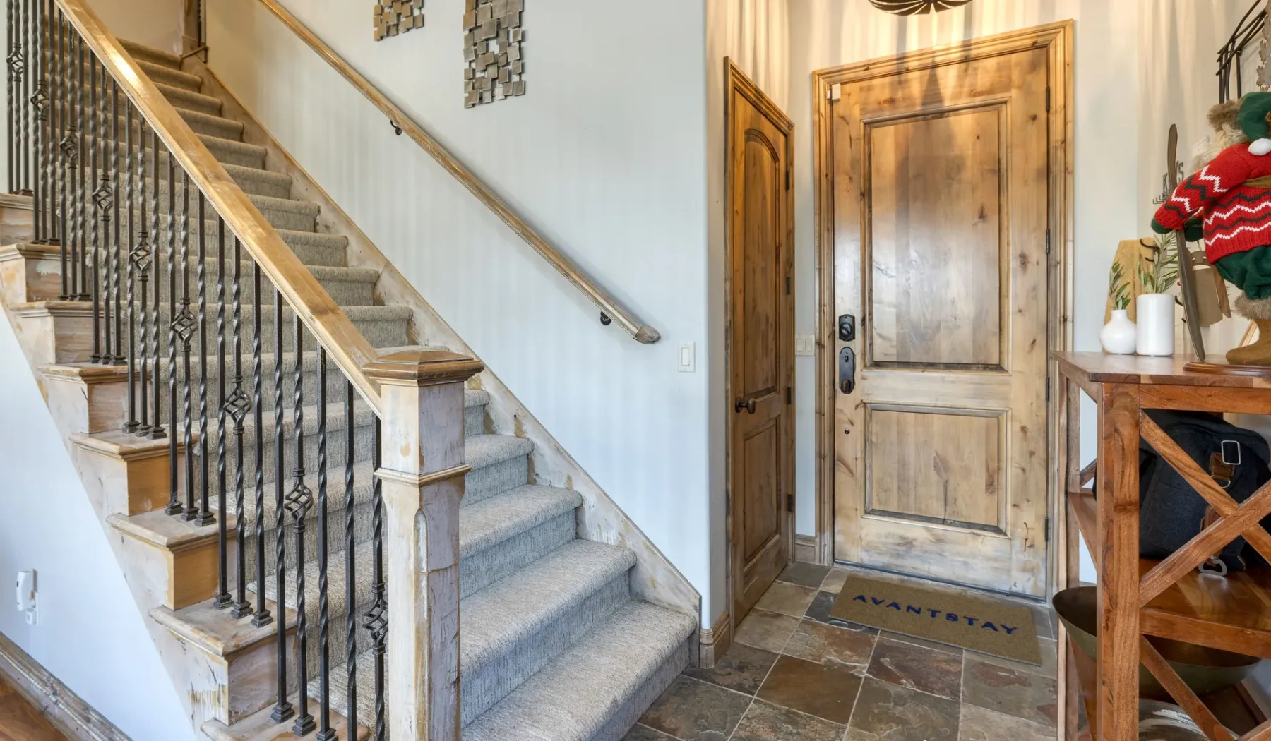 An entryway with a wooden door and a staircase with a carpeted runner.