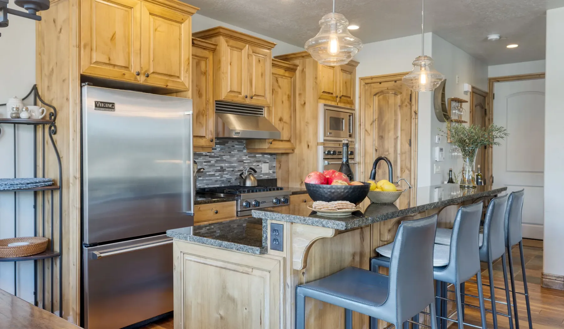 A kitchen with wooden cabinets, stainless steel appliances, and an island with seating.