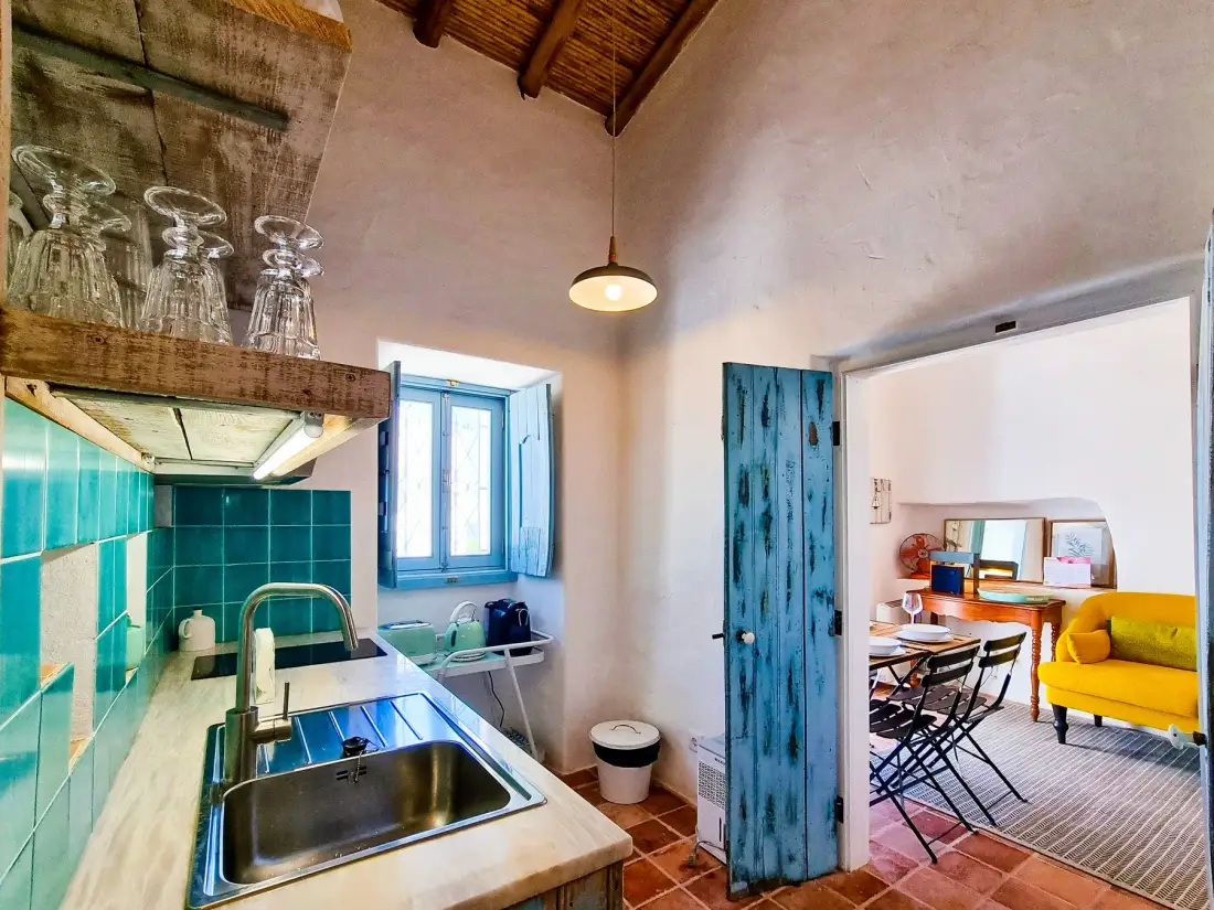 Una cocina compacta da a una zona de comedor y estar con un sillón amarillo.
