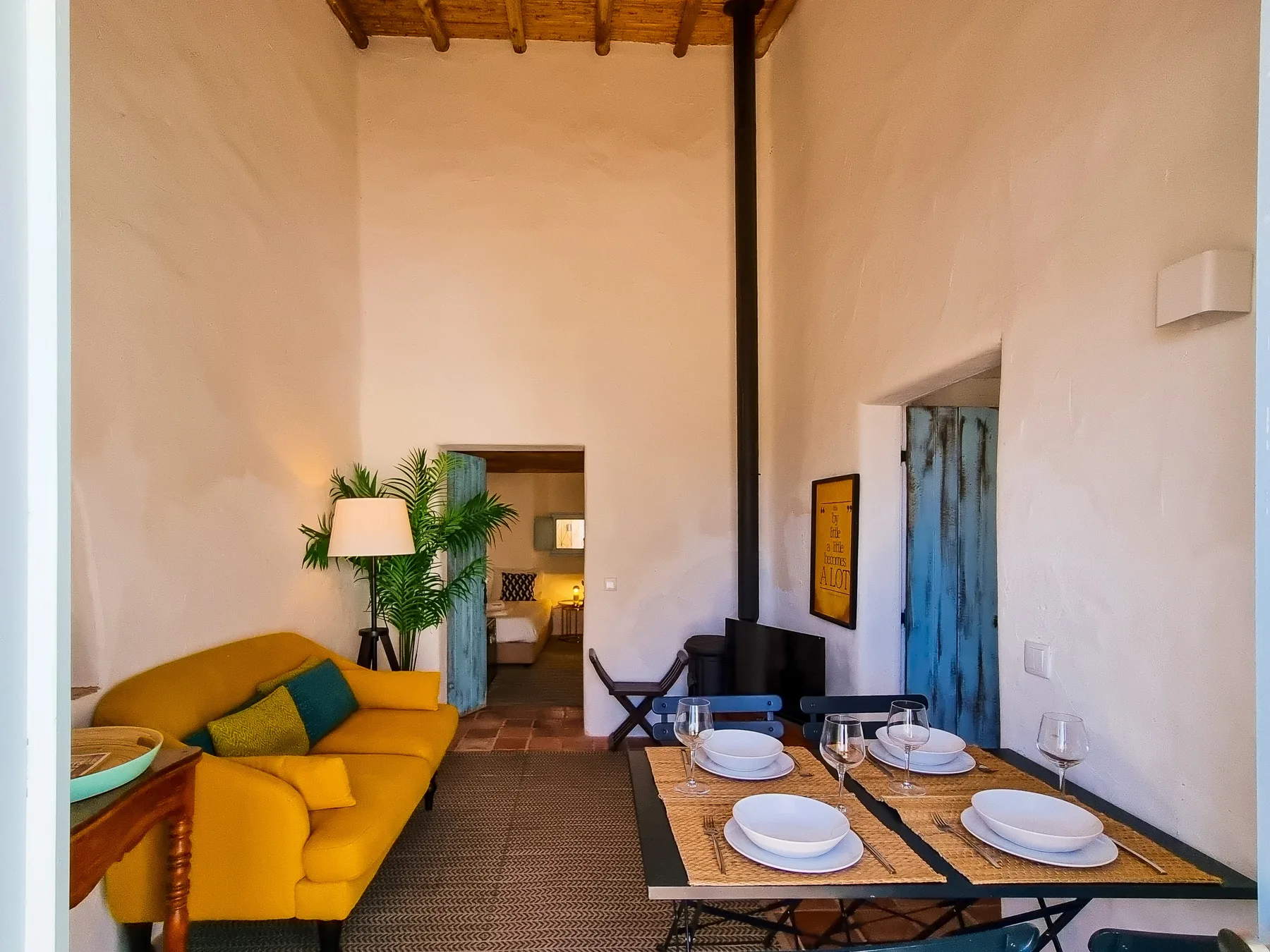 Una zona rústica de estar y comedor con asientos amarillos y una mesa puesta.