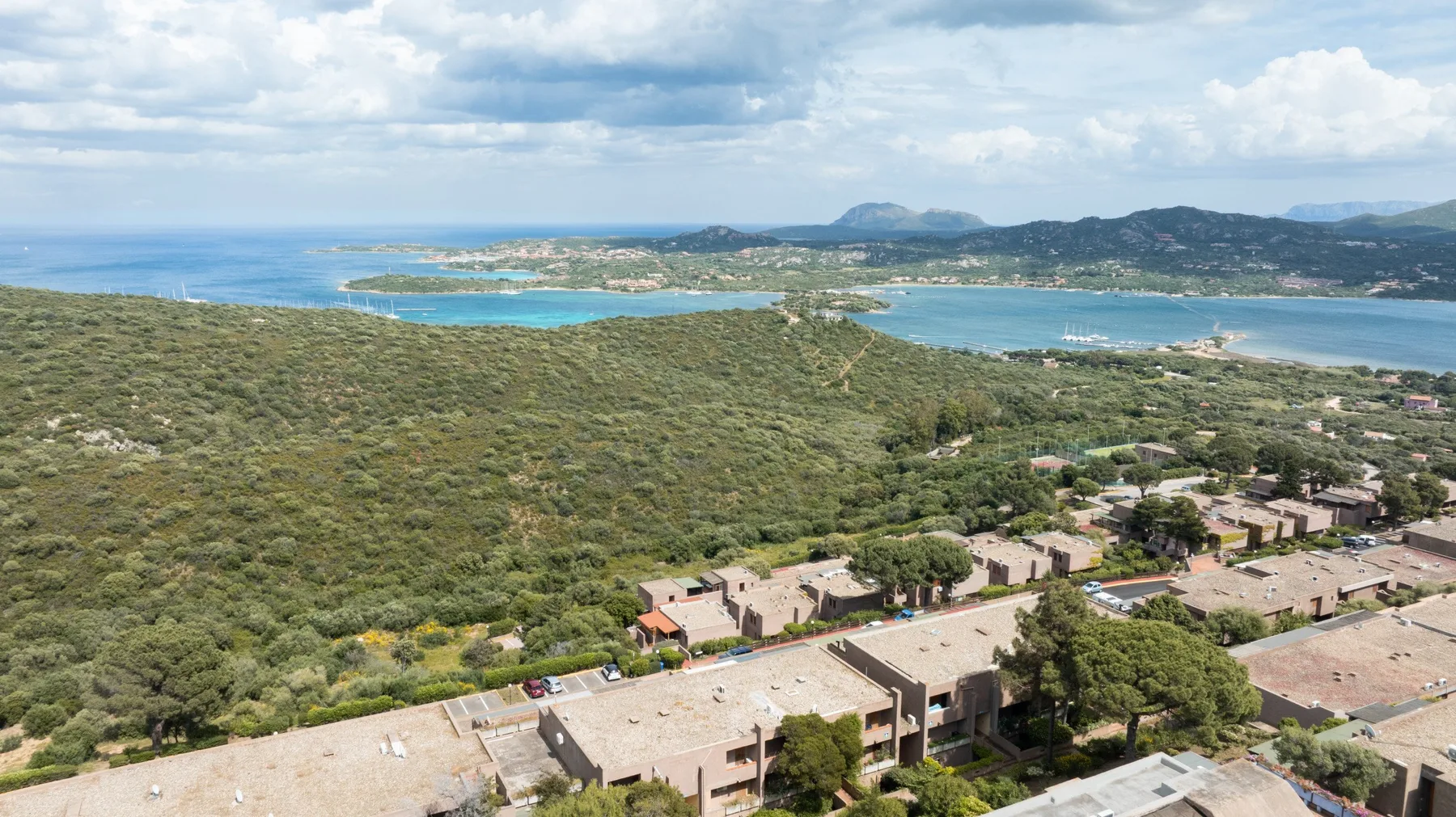 Vista aérea de un asentamiento costero junto a bahías turquesas y colinas verdes.