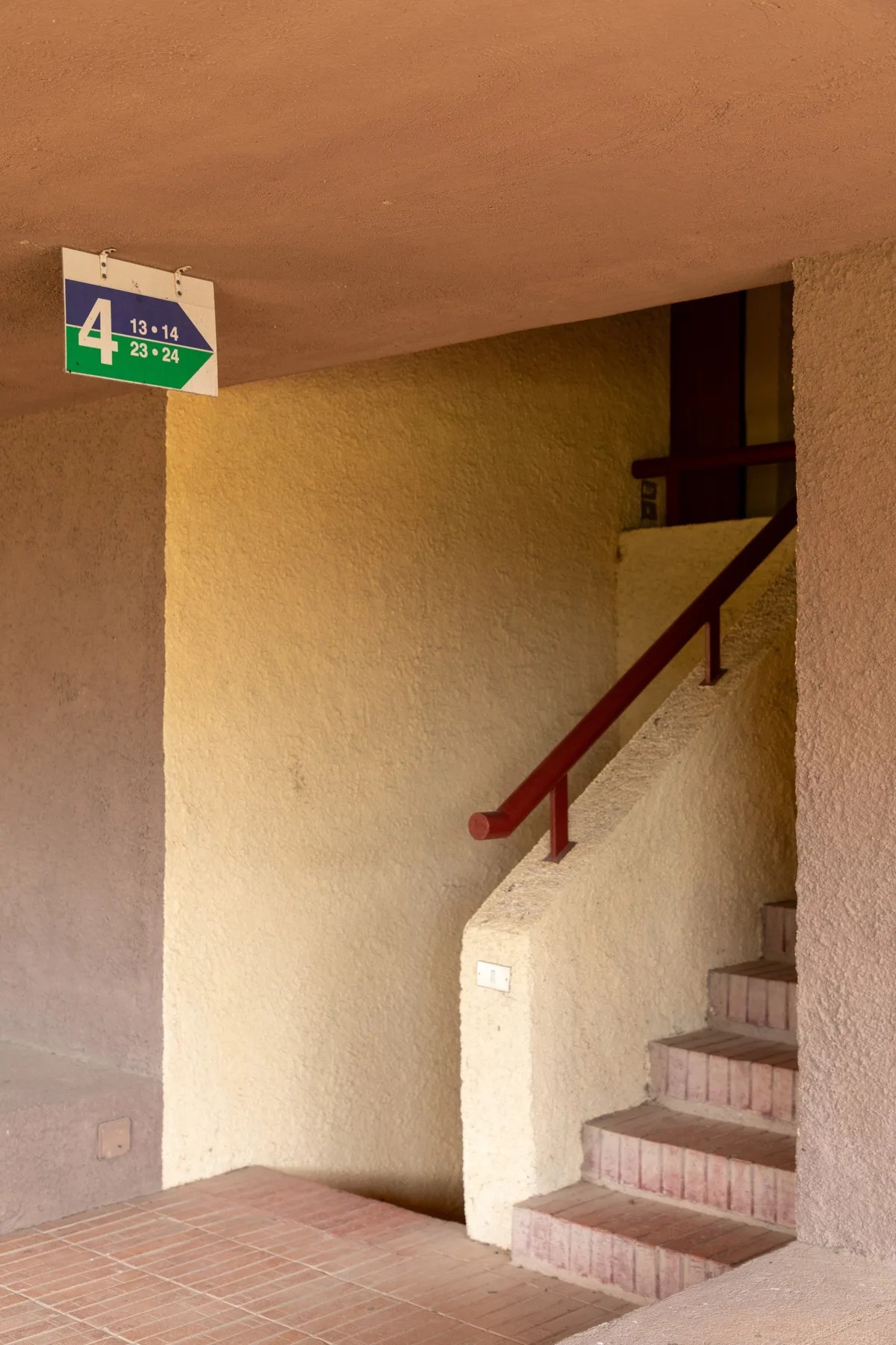 Una escalera interior con peldaños de baldosas y una barandilla de madera oscura.