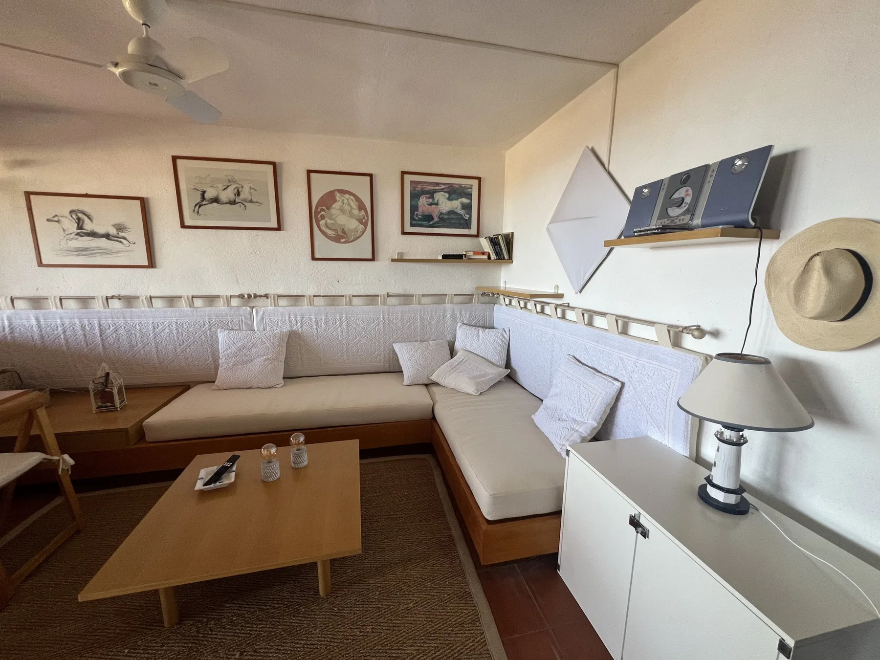 Una sala de estar con asientos en forma de L, cuadros enmarcados y una mesa de centro.