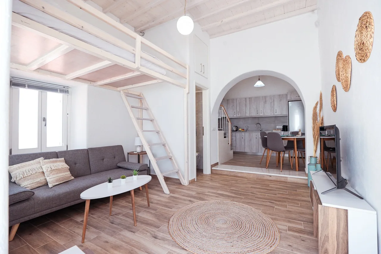 A bright living room with a raised sleeping loft and an adjoining dining area.