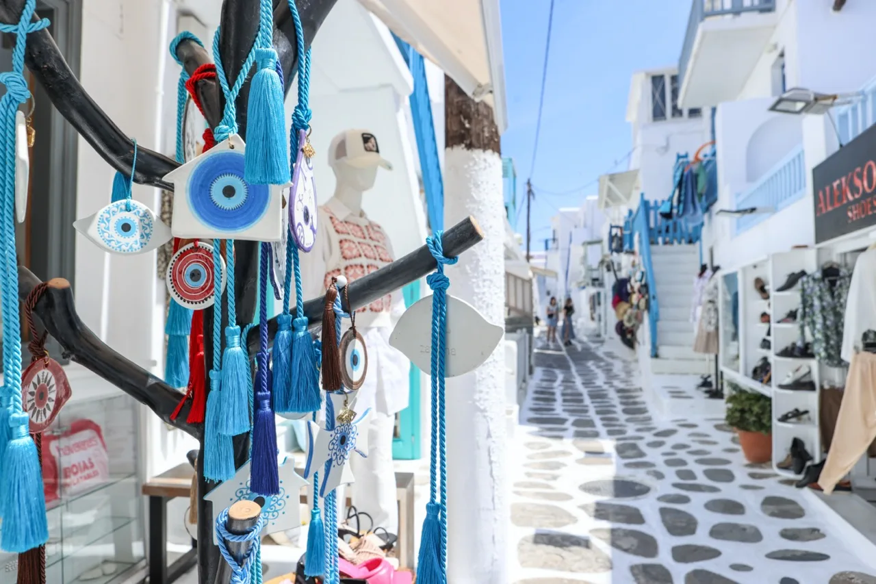 A narrow pedestrian street lined with white buildings and colorful hanging souvenirs.