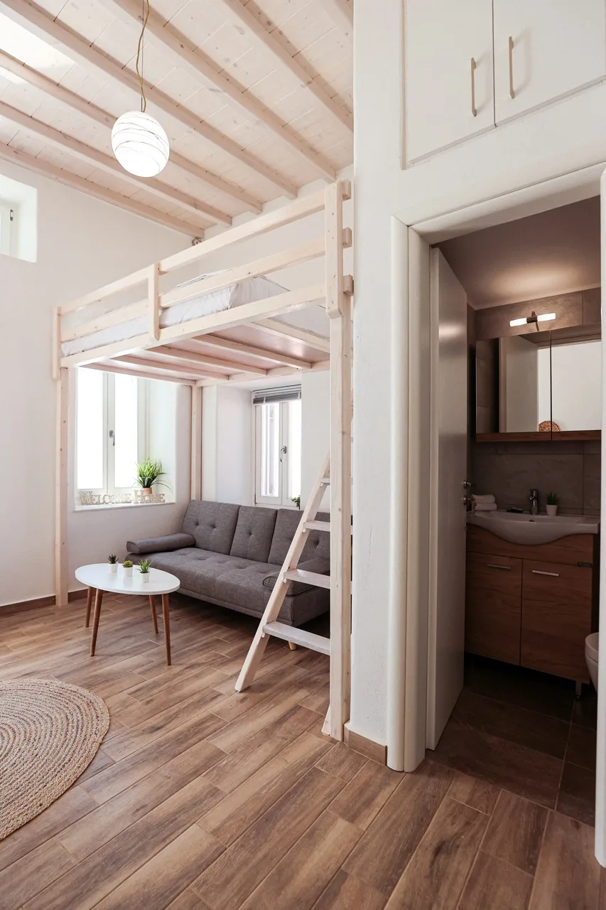 A bright living area with a raised sleeping platform and a small bathroom doorway.