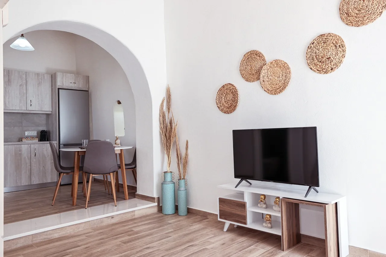 A living area with a television and woven wall decorations beside a dining nook.