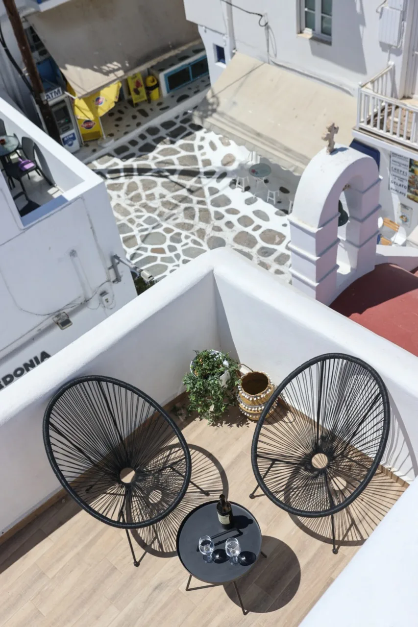 A rooftop terrace with two dark woven chairs and a small round table.