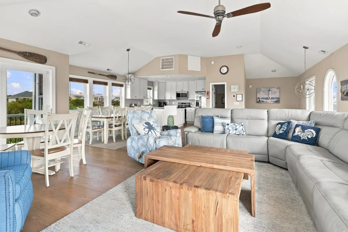 A bright open-plan living and dining area with a kitchen in the background.