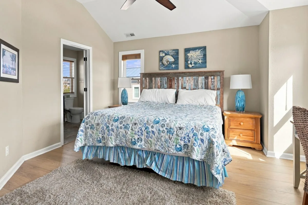 A bedroom with a large bed, bedside tables, and framed artwork.