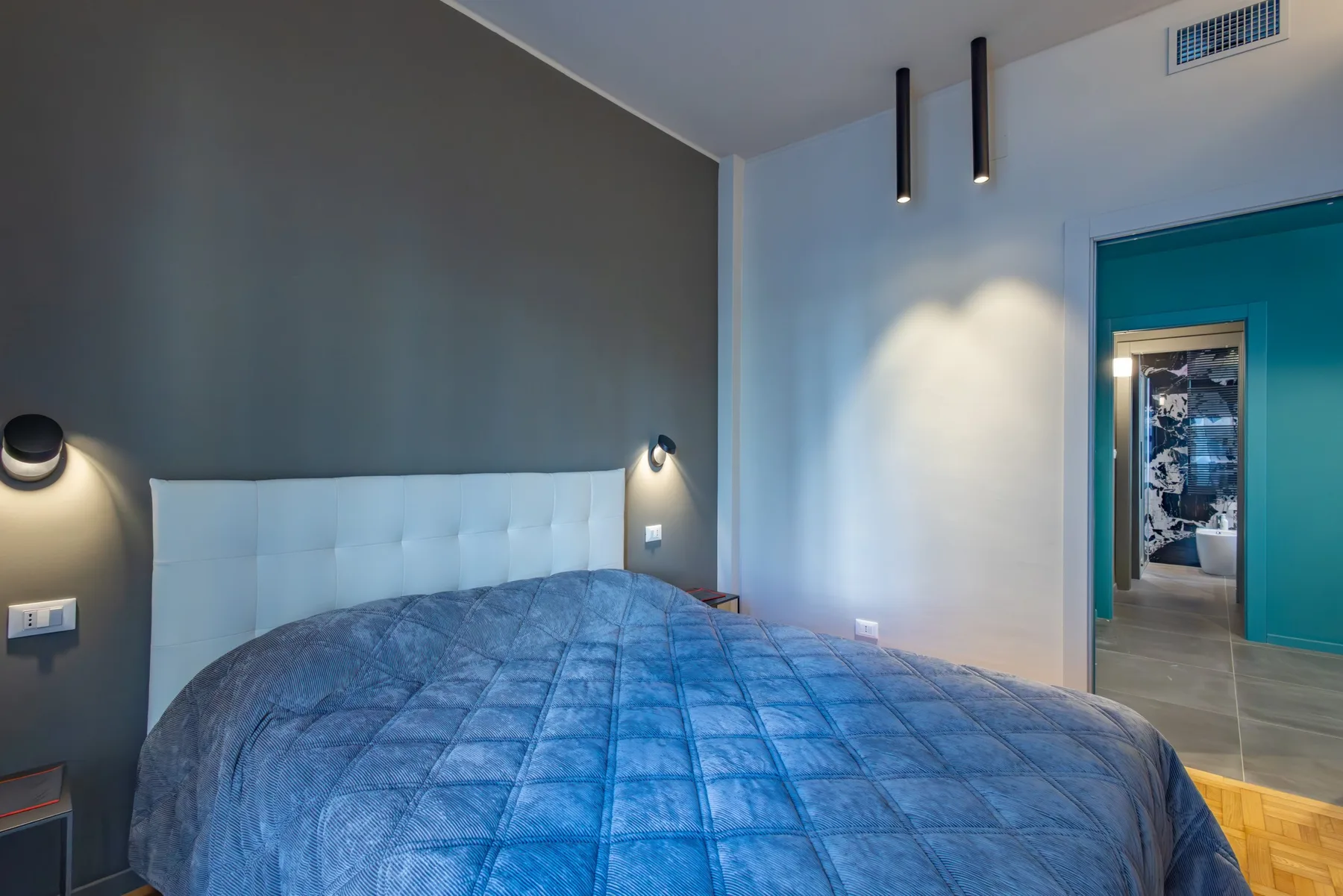 A bedroom with a bed beneath a padded headboard.