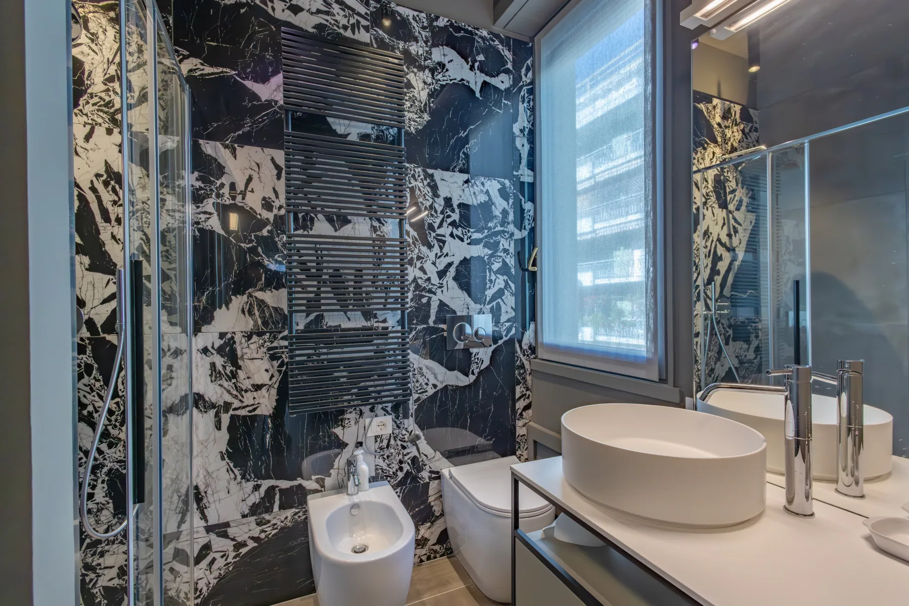 A modern bathroom with a vessel sink, toilet, and glass shower.