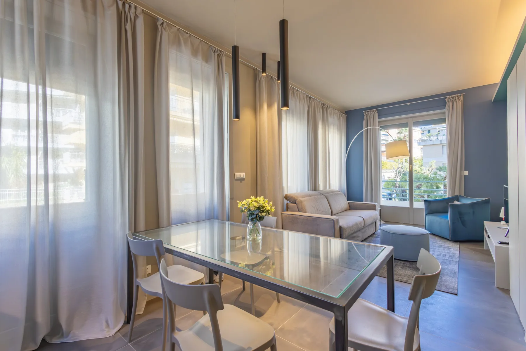 A bright living and dining area with a glass table and seating.