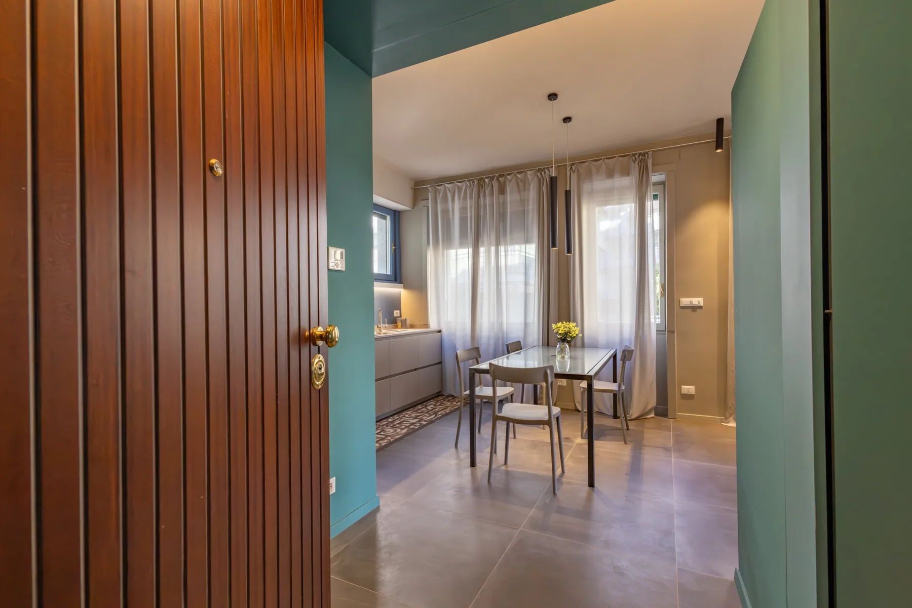 Dining area with a table and chairs beside a curtained window.