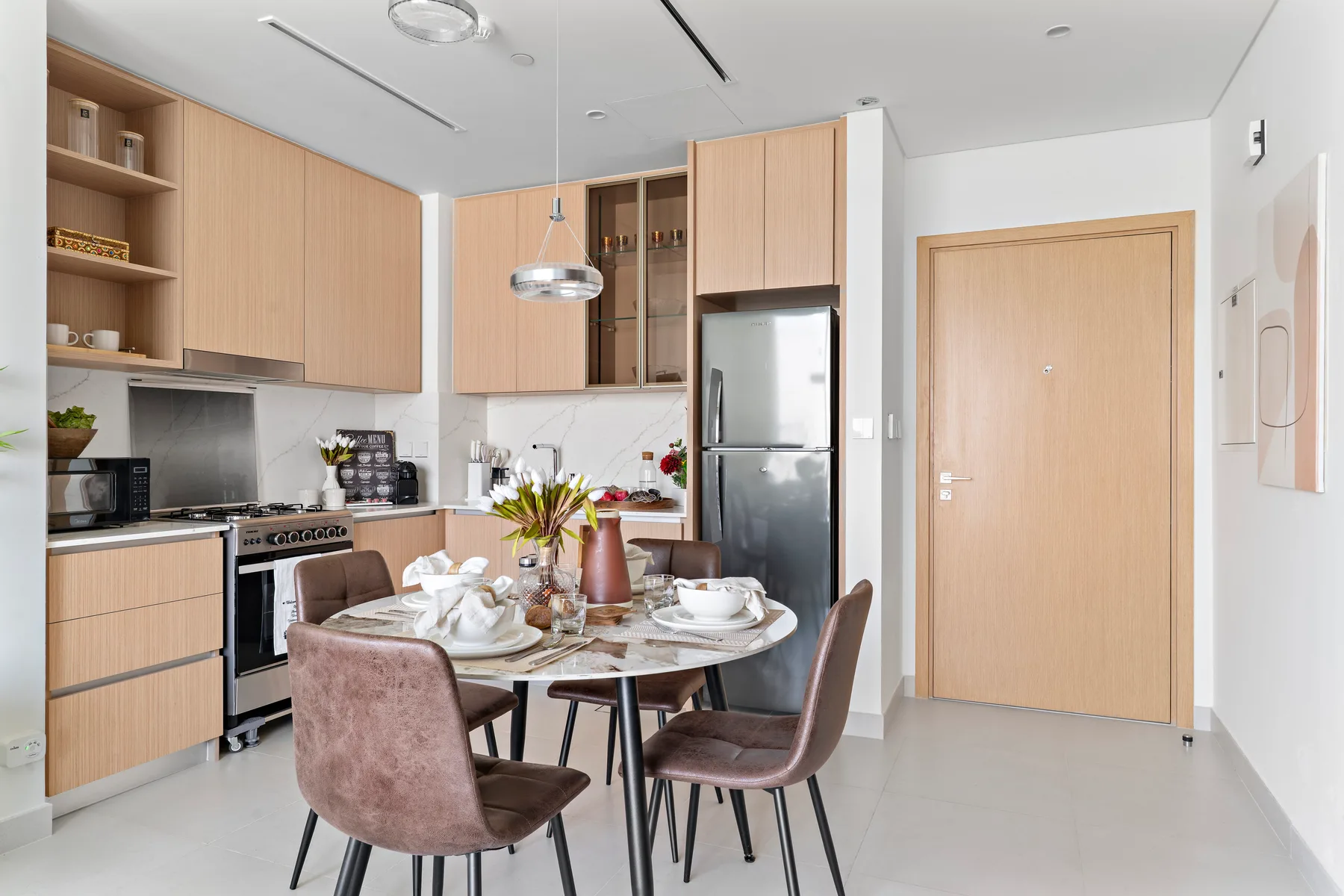 A bright kitchen and dining area with wood cabinetry and a set table.