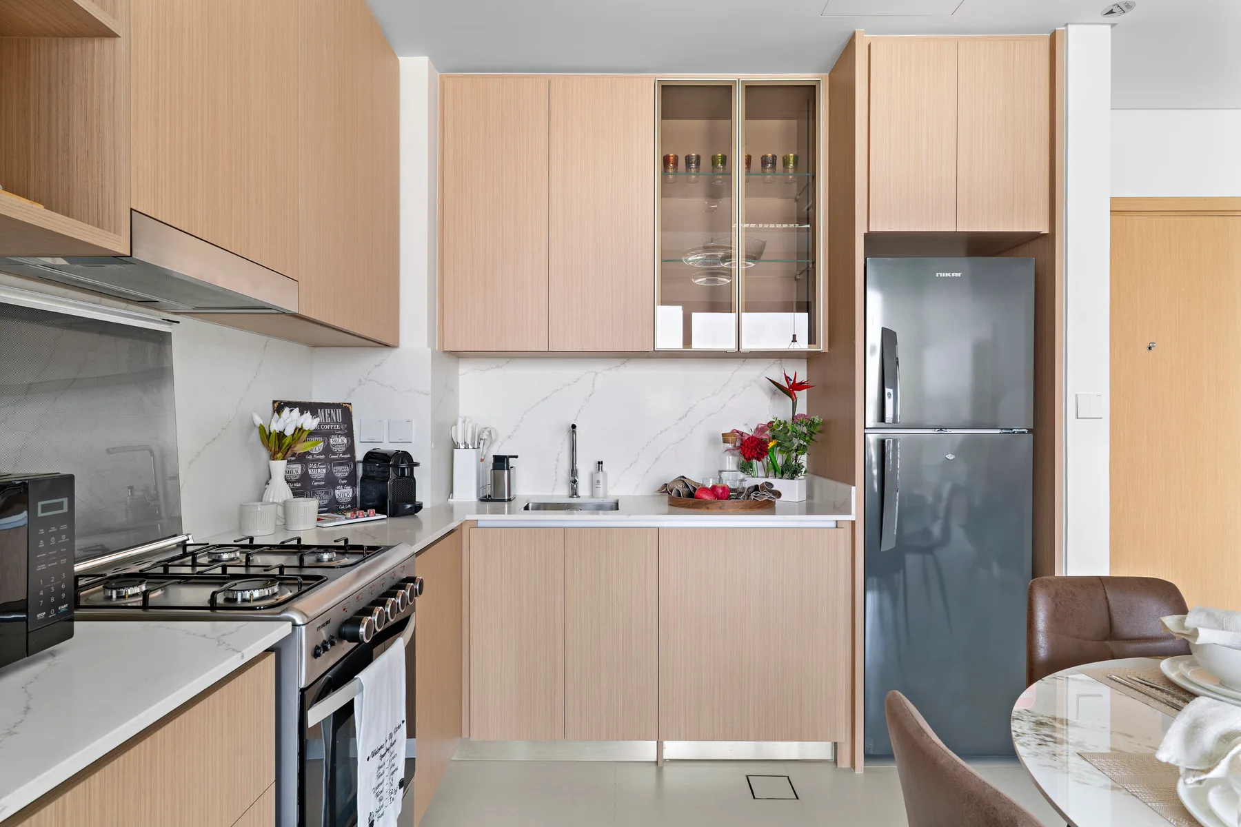 A modern kitchen with light wood cabinets, a countertop, and a dining table.