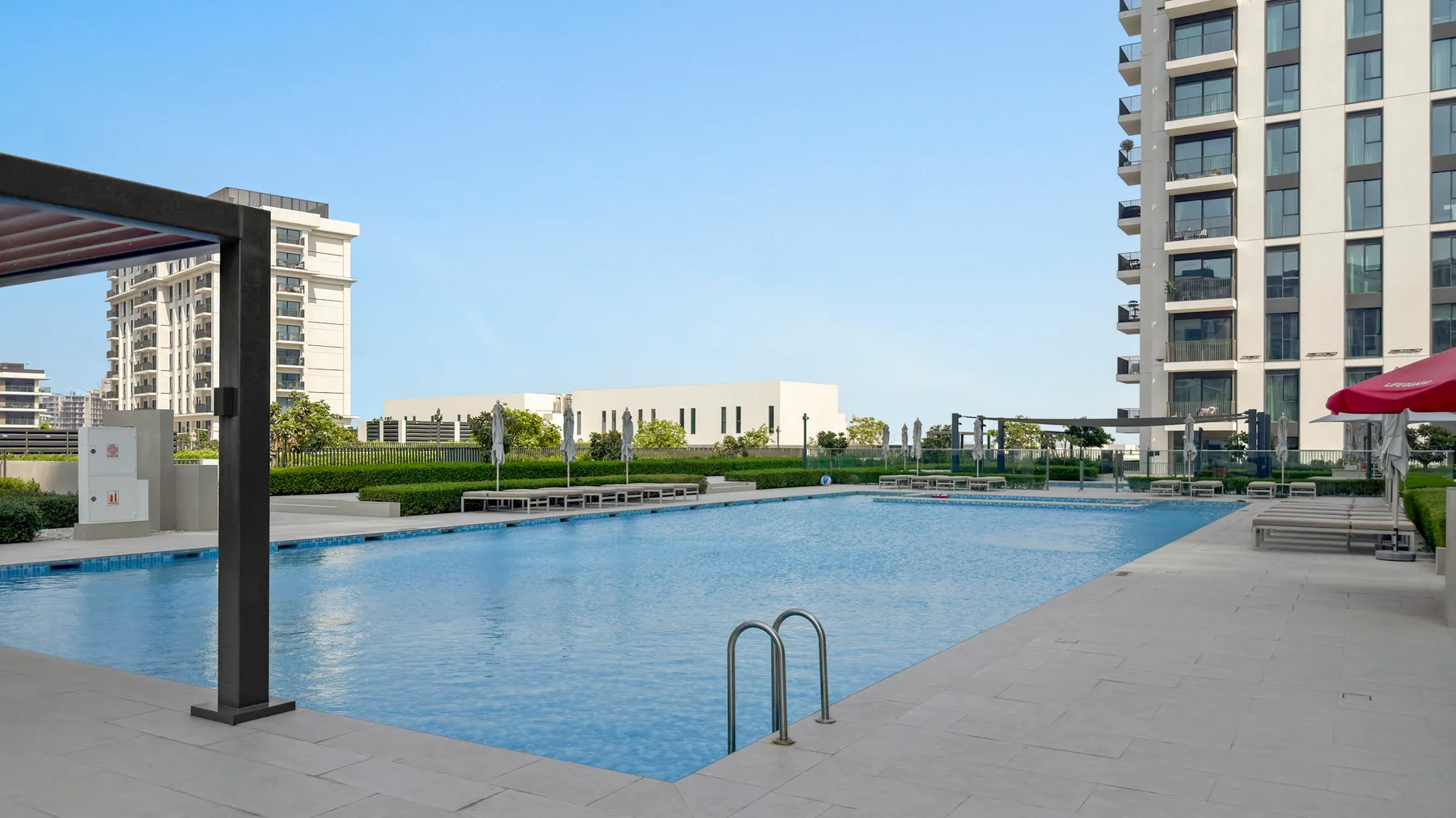 An outdoor swimming pool sits beside modern apartment buildings.