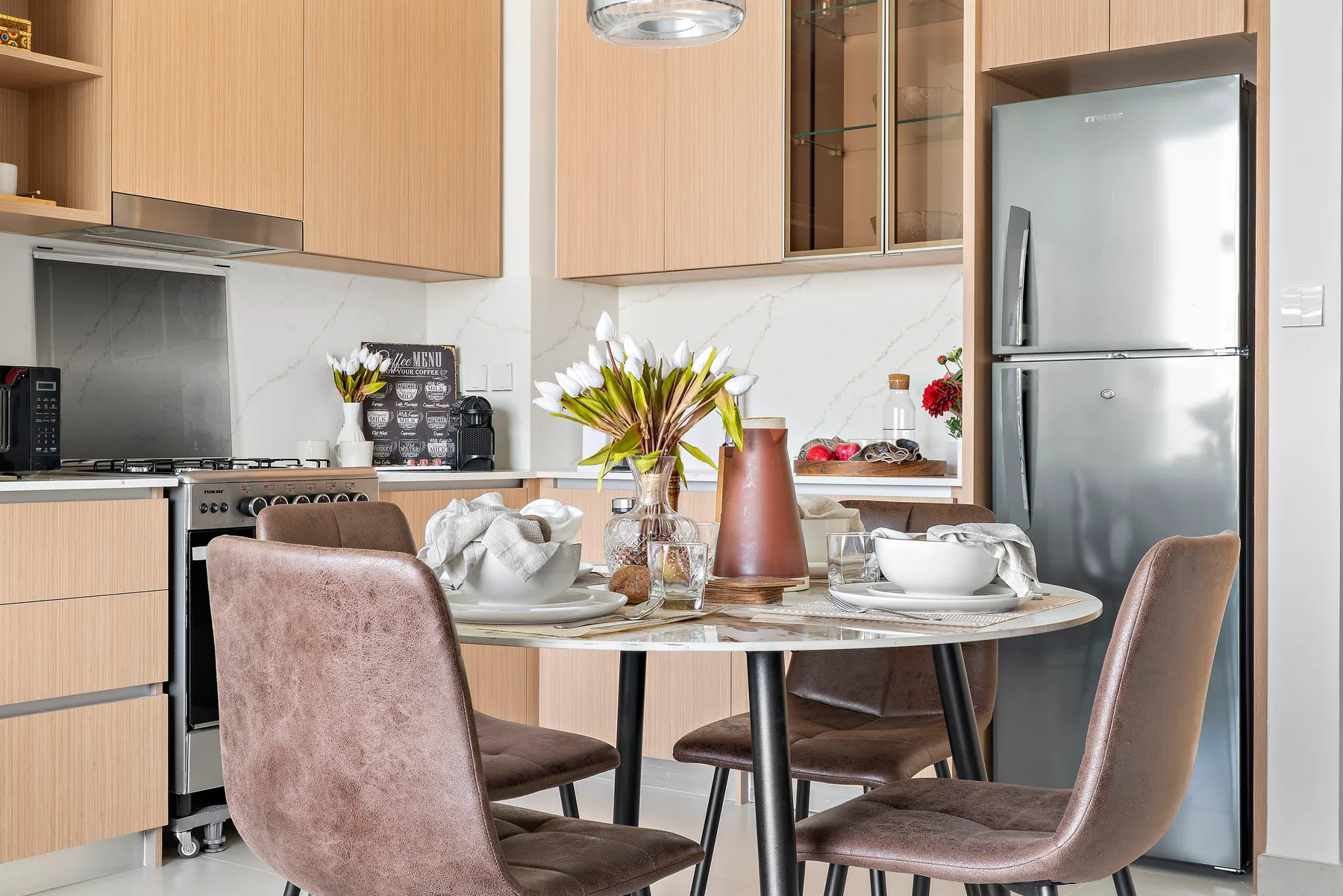 A dining table set for a meal sits beside a modern kitchen.