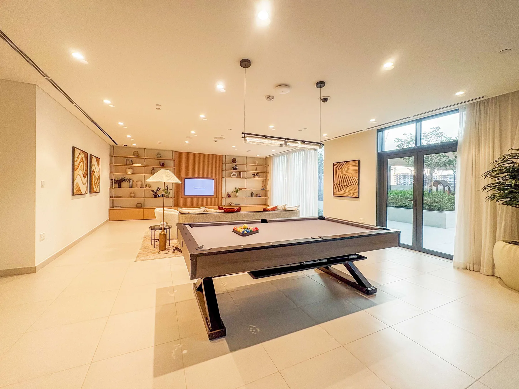 A bright recreation room features a pool table and a lounge area.