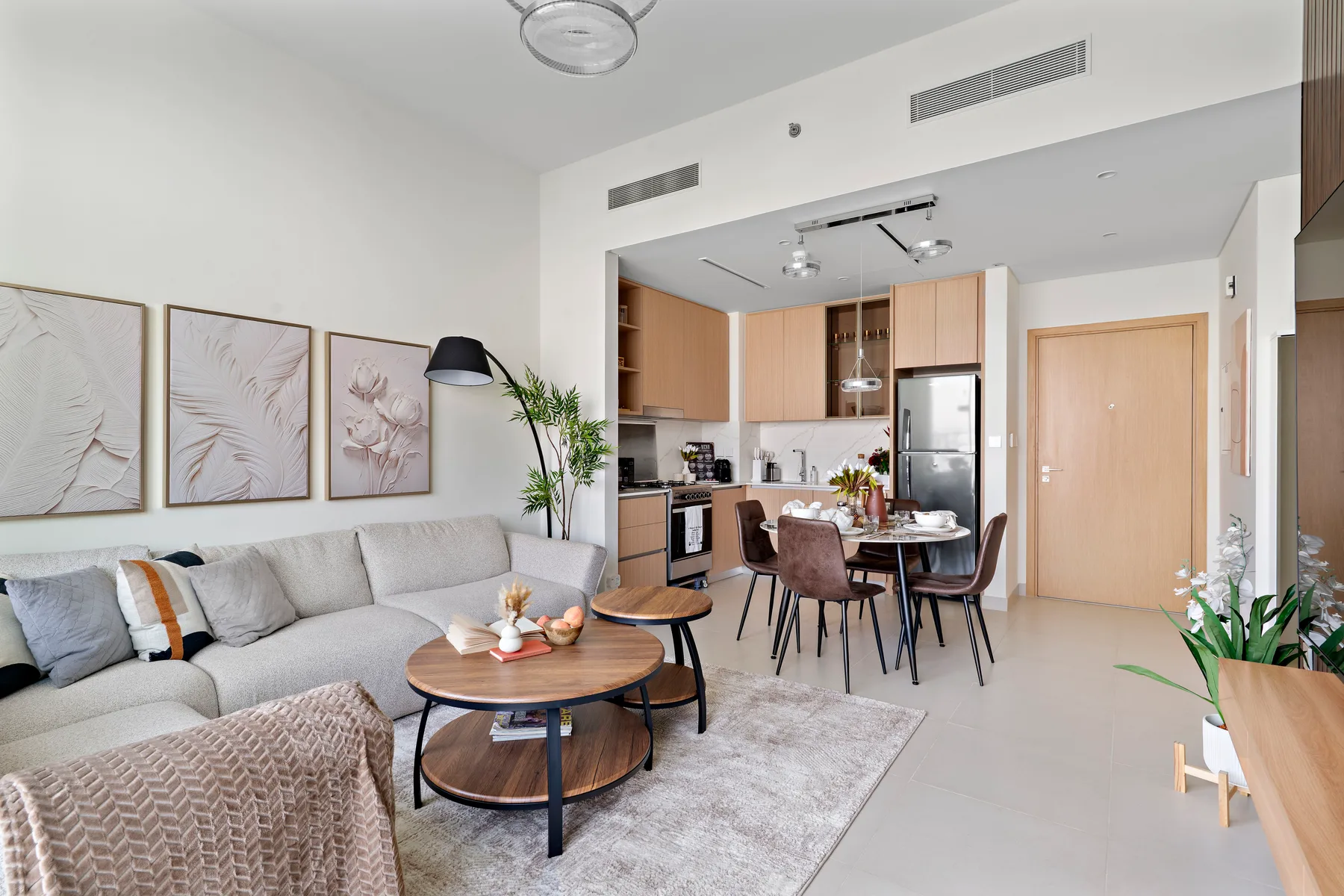 A bright open-plan living room and kitchen with a dining table and seating.