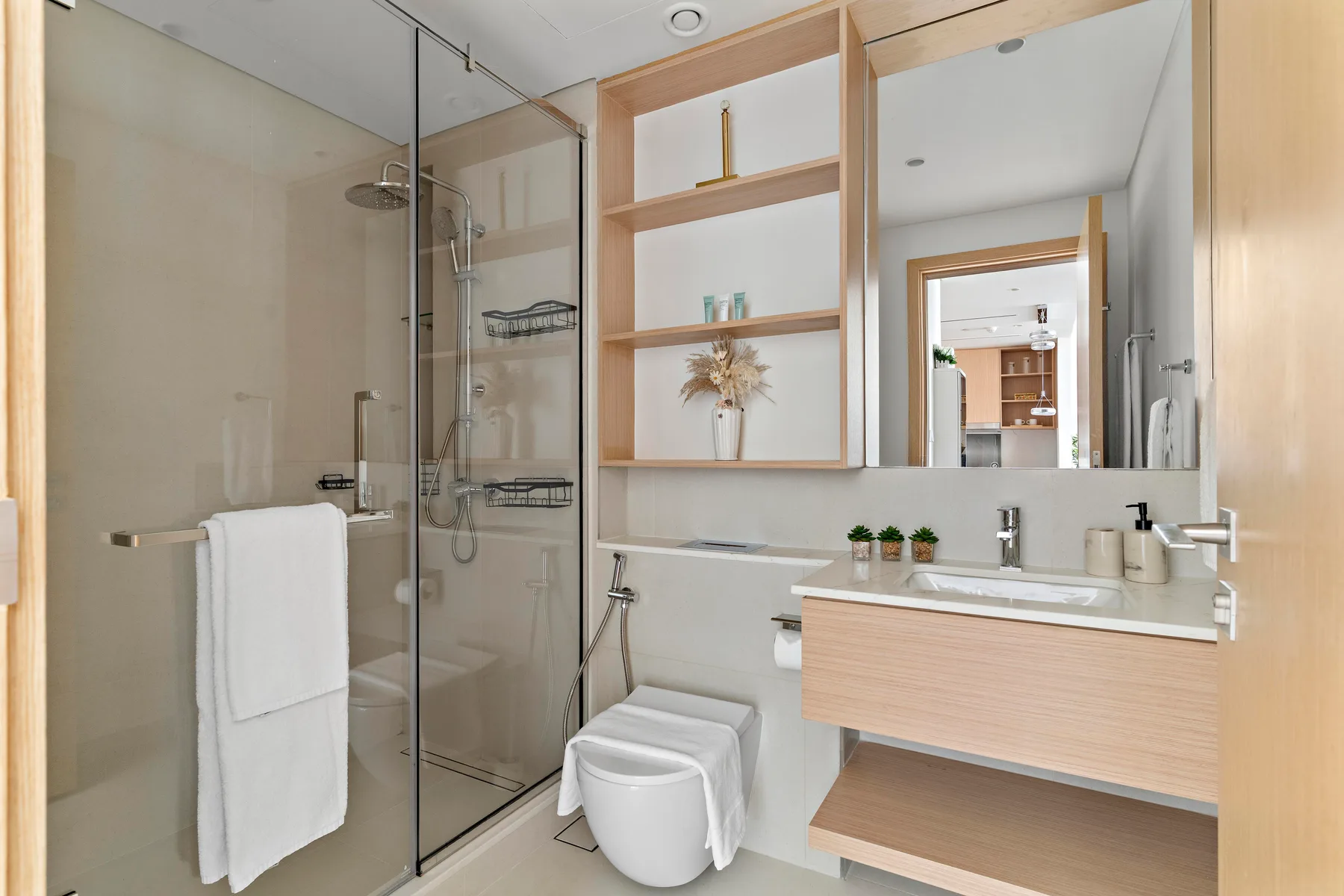 A bright bathroom with a glass shower, toilet, and vanity.