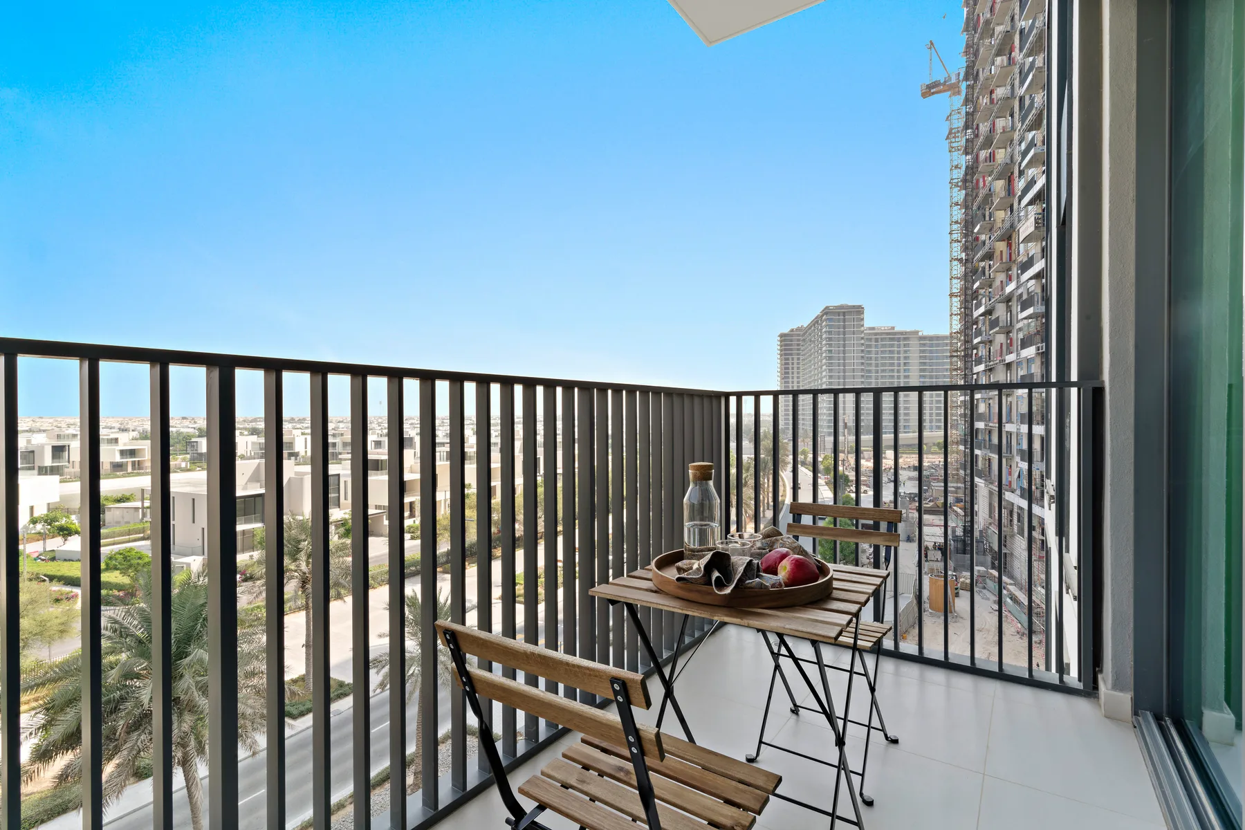 A balcony seating area overlooks nearby buildings and greenery.