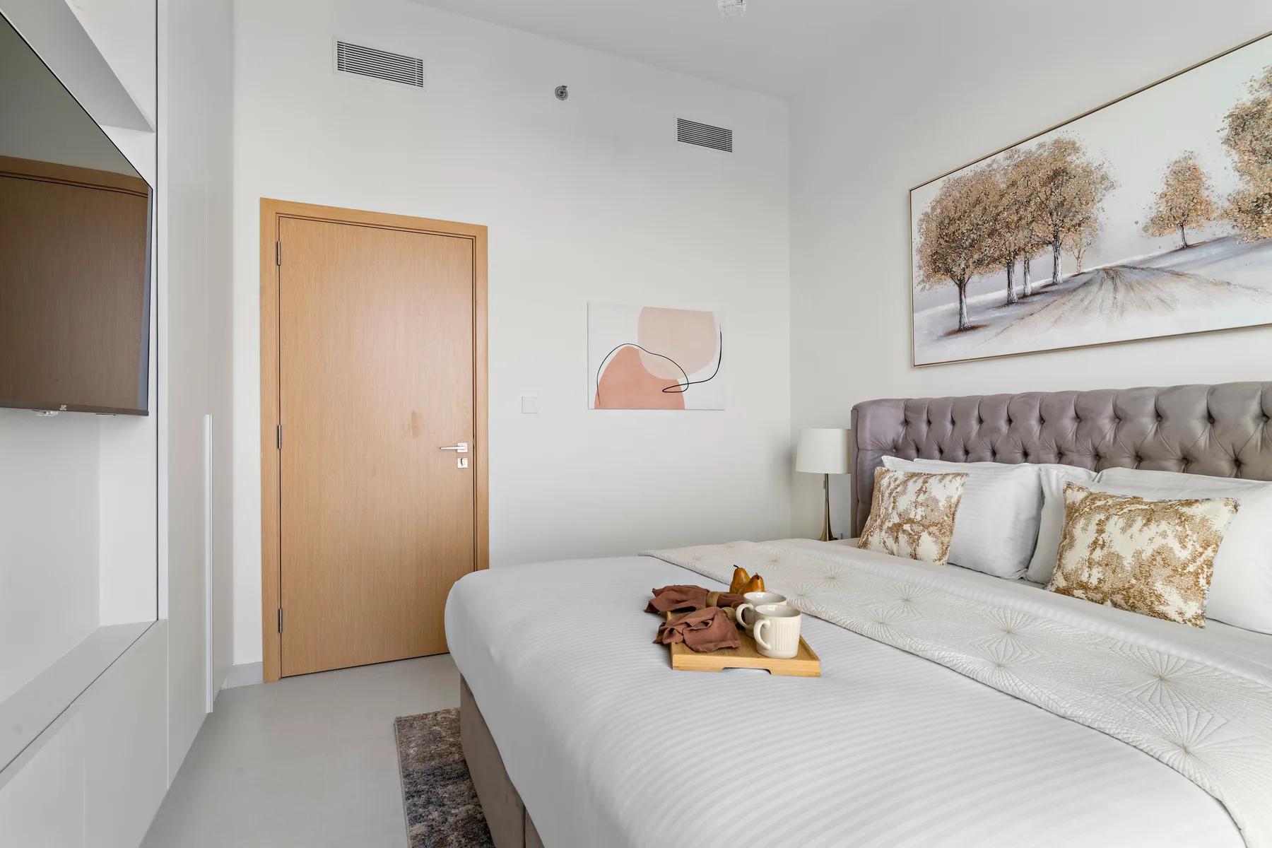 A bright bedroom with a large bed and framed artwork above the headboard.