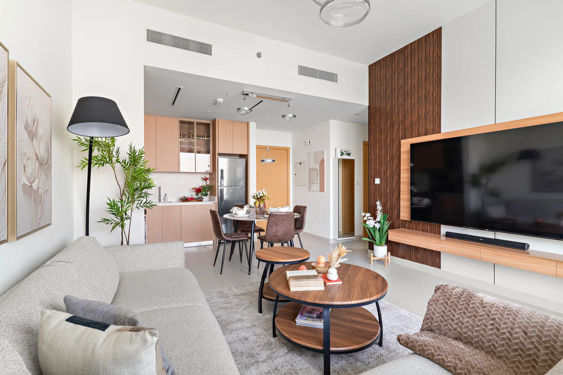 A bright living room with a dining area and a large television.