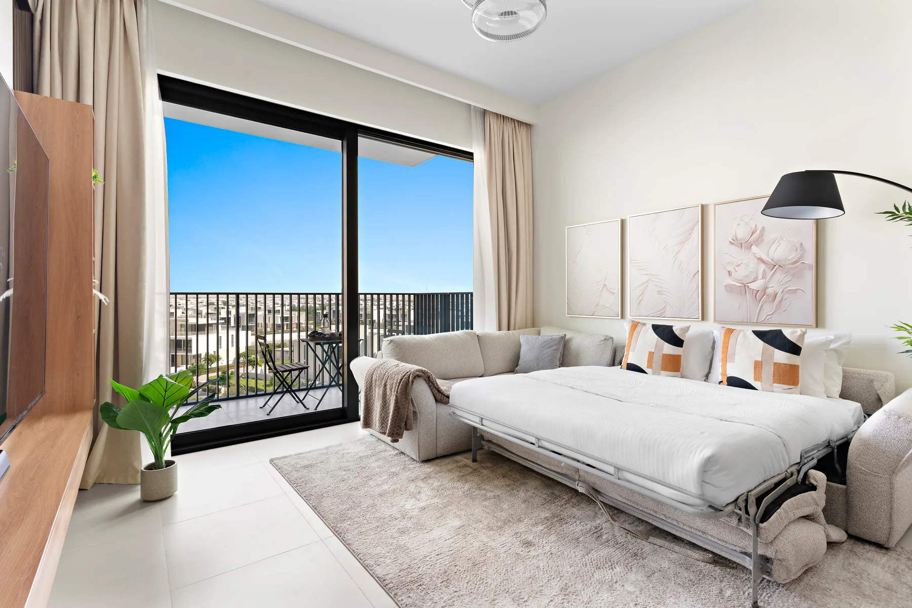 A bright bedroom with a bed, seating, and large glass doors opening onto a balcony.