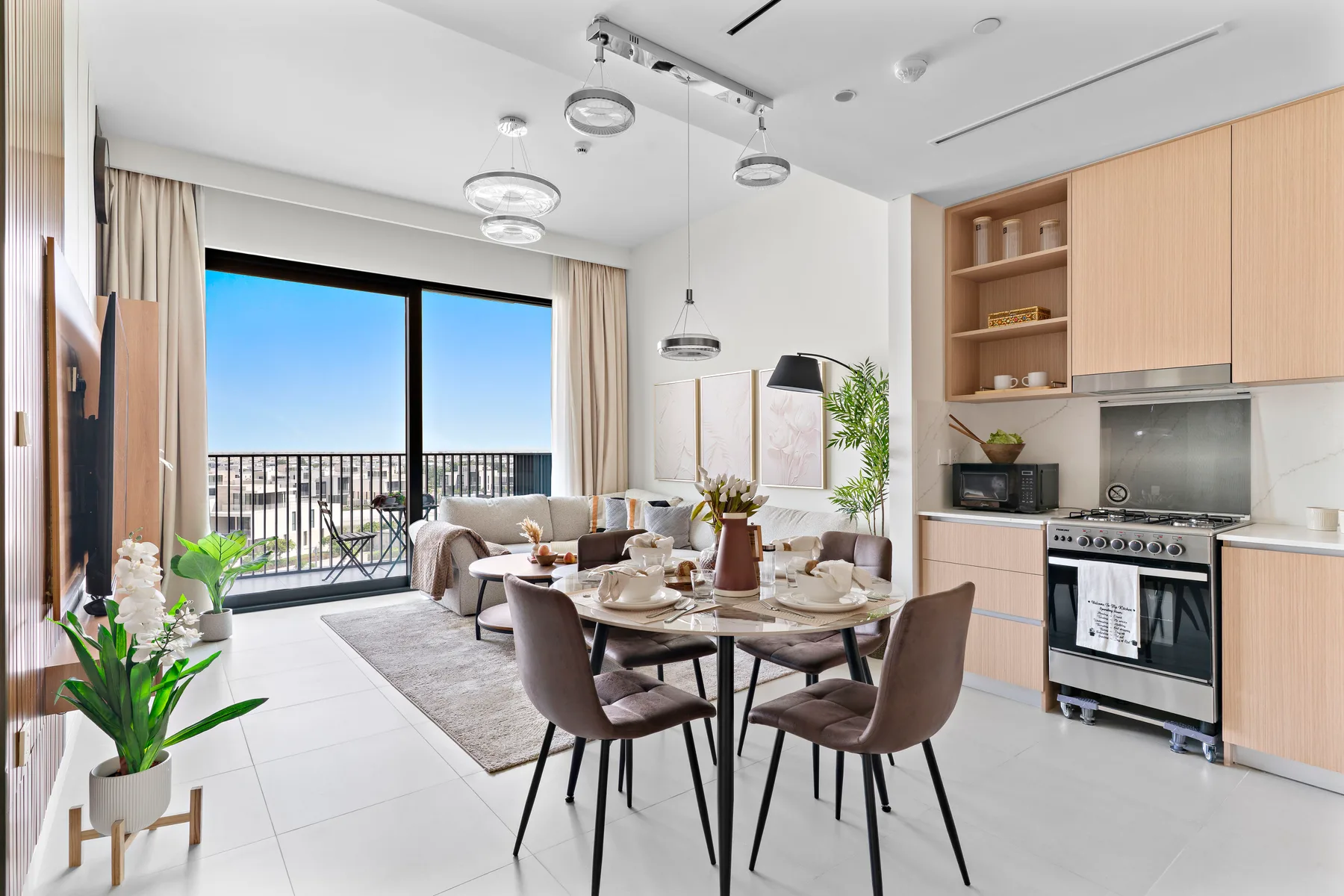 A bright open-plan living and dining area with a kitchen and balcony doors.